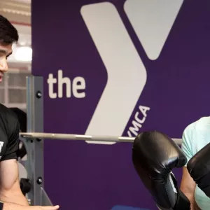 A member with boxing gloves works with a YMCA personal trainer.