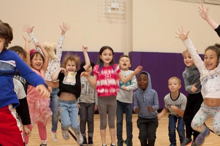 Class of preschool kids jumping in YMCA gym