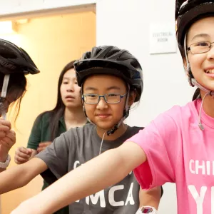 Girls with bike helmets wearing Chinatown YMCA tee shirts.